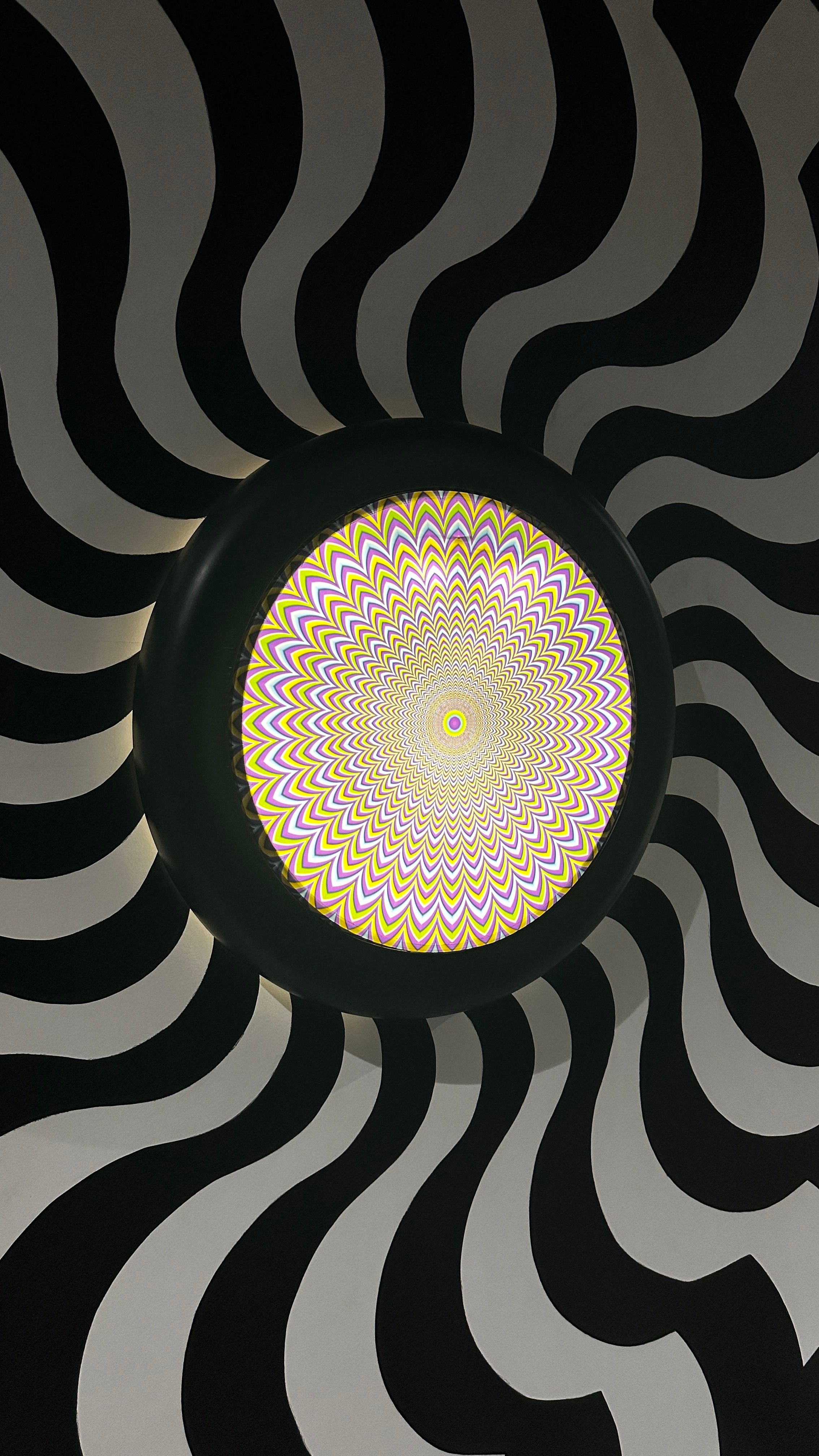 Black and white wavy pattern with a colorful spiral center. Ideal for optical illusion concepts.