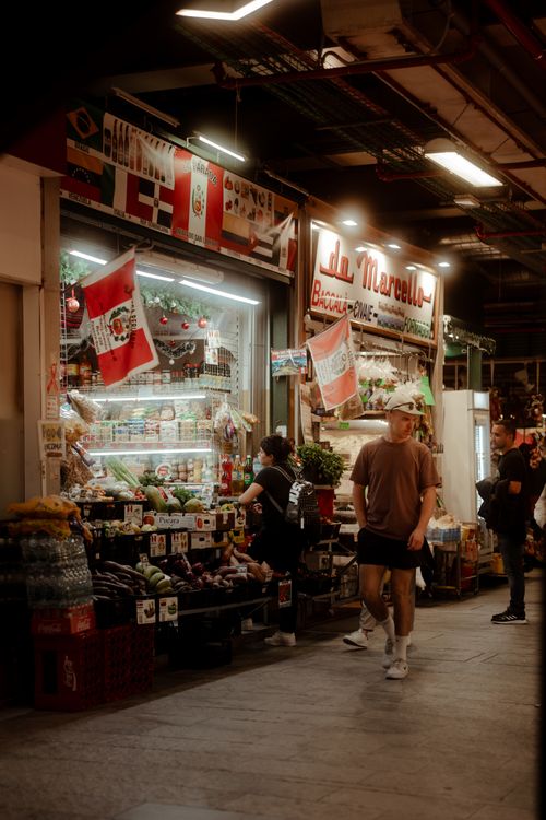 Free A vibrant indoor market scene featuring diverse produce, flags, and shoppers in motion. Stock Photo