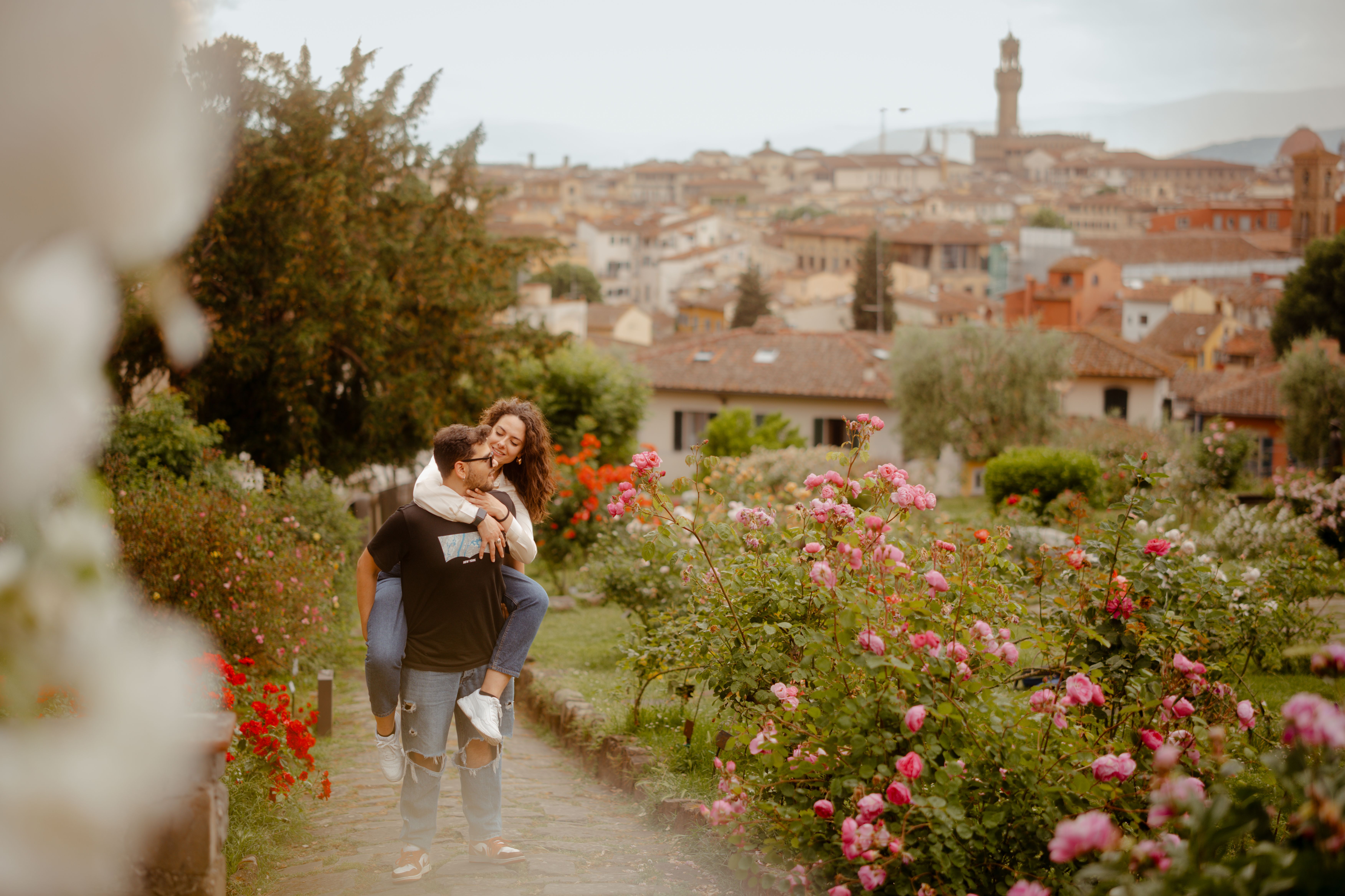 A joyful couple in a vibrant garden with Florence's skyline in the background, offering a romantic atmosphere.
