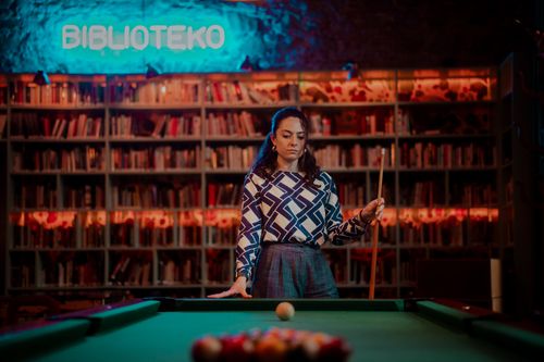 Free A woman focusing on a billiards game in a cozy library with colorful lighting. Stock Photo