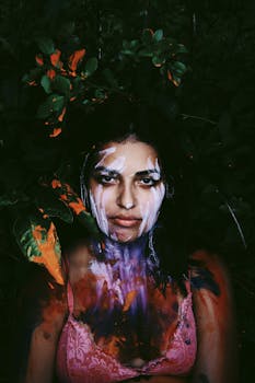 这幅充满活力的艺术肖像描绘了一位全身彩绘、被树叶围绕的女性