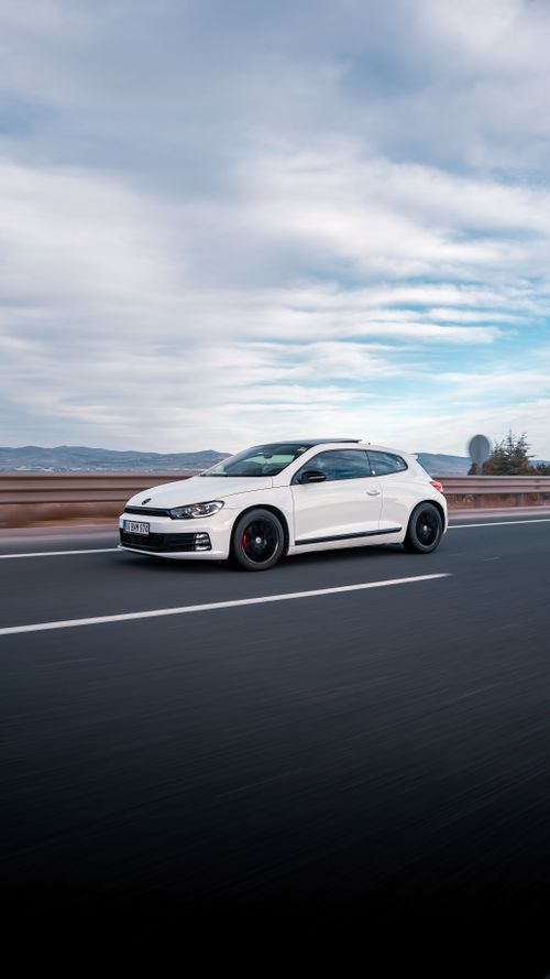 Free Sleek white car speeding on a highway in Ankara, Türkiye under a partly cloudy sky. Stock Photo