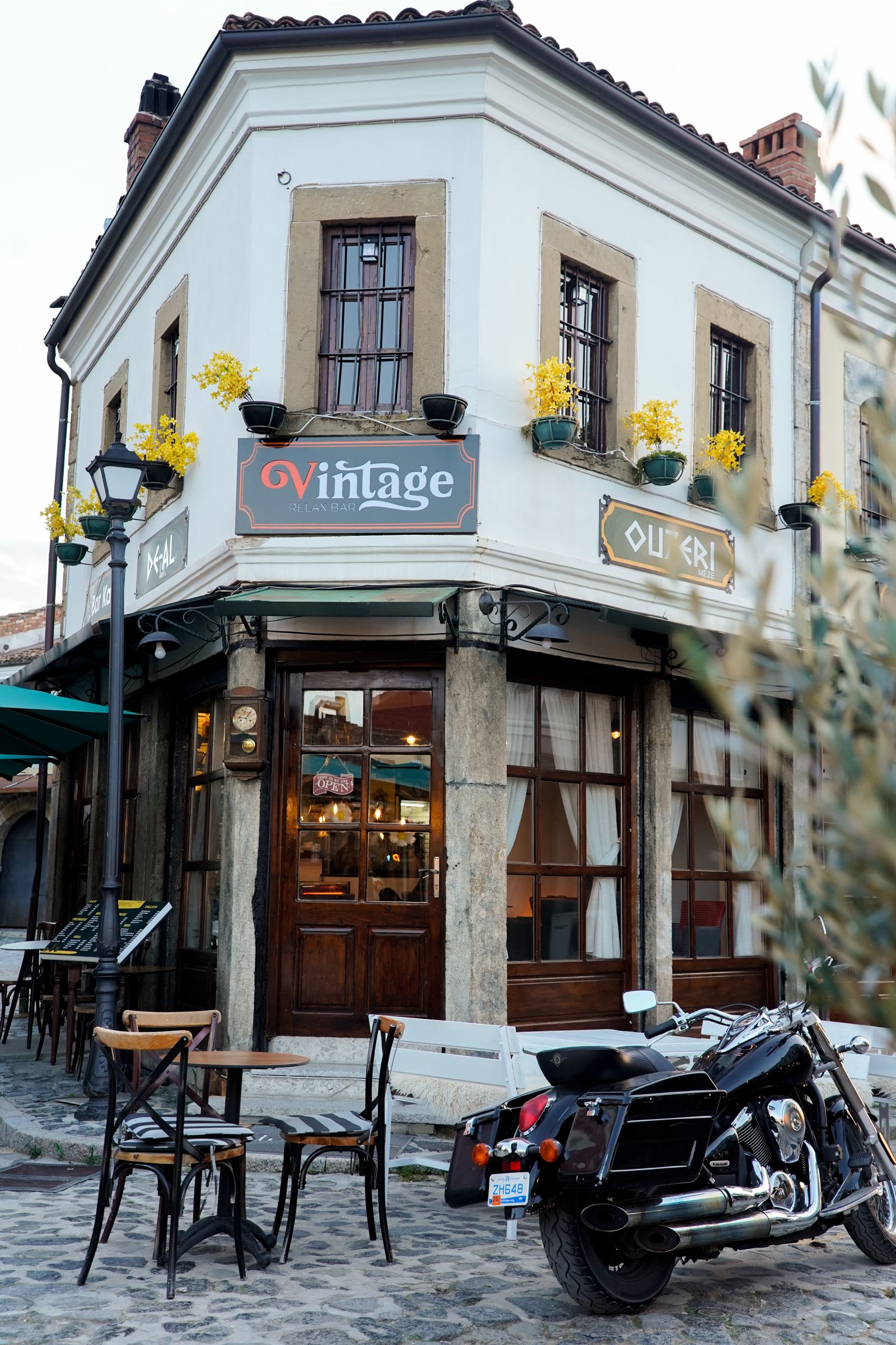 Café de style vintage avec tables en terrasse à l’angle d’une rue pavée de Korçë, Albanie