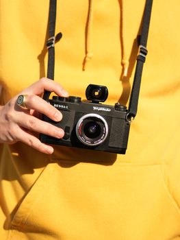 Young adult holding a Bessa-L film camera, wearing a vibrant yellow hoodie.