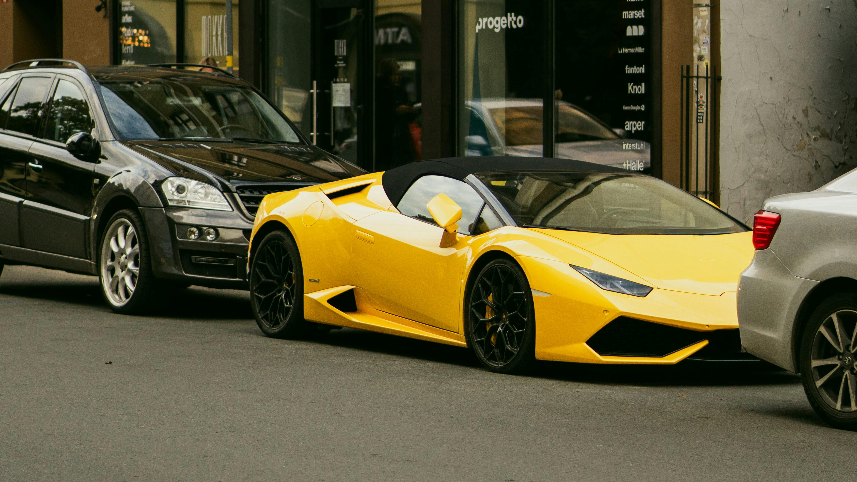 A vibrant yellow sports car parked between two other vehicles on a city street.
