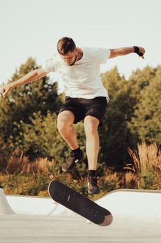 Dynamic shot of a skateboarder executing a kickflip in an outdoor skatepark beneath clear skies.