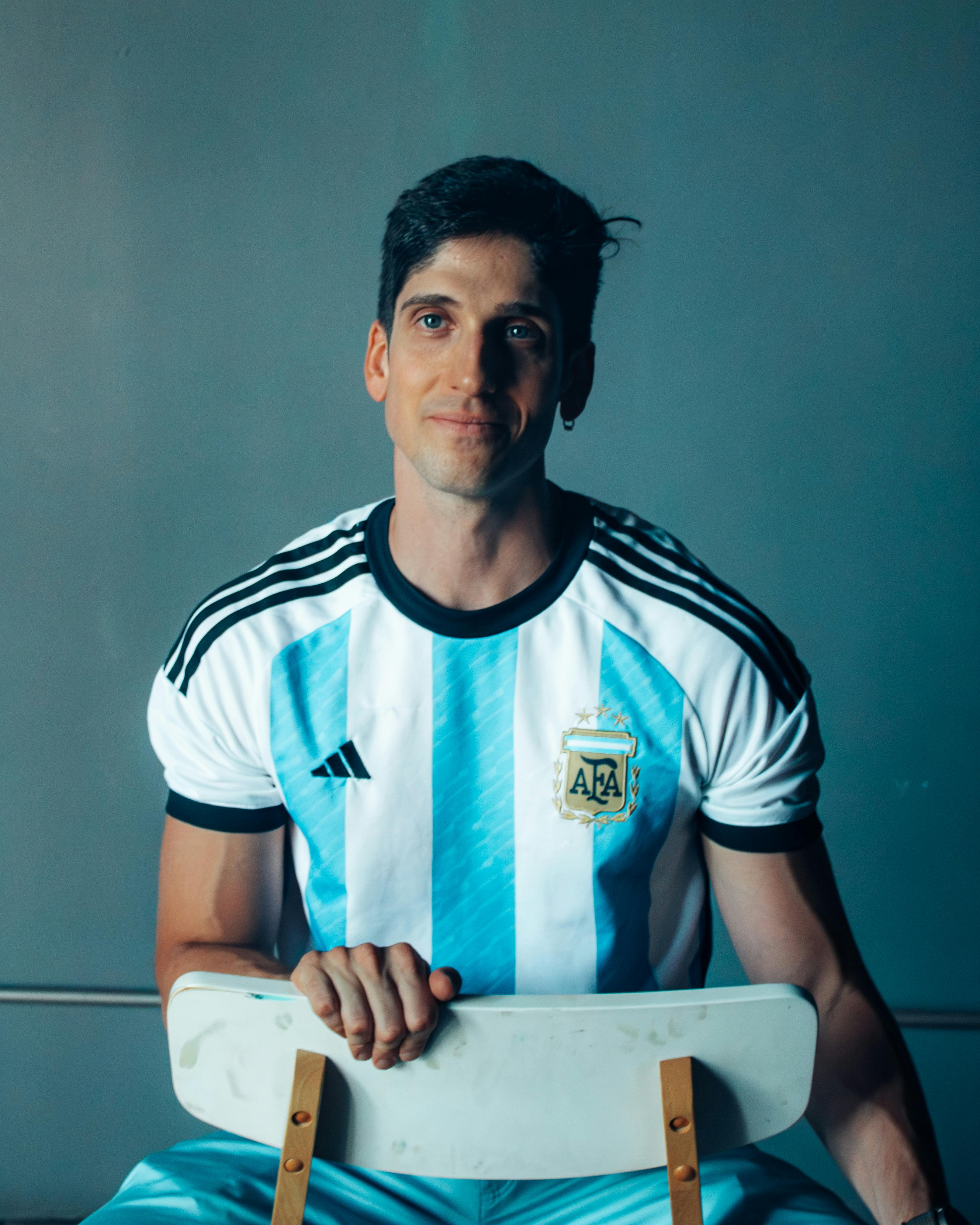 Man wearing Argentine football jersey, smiling indoors against a neutral background in Buenos Aires.