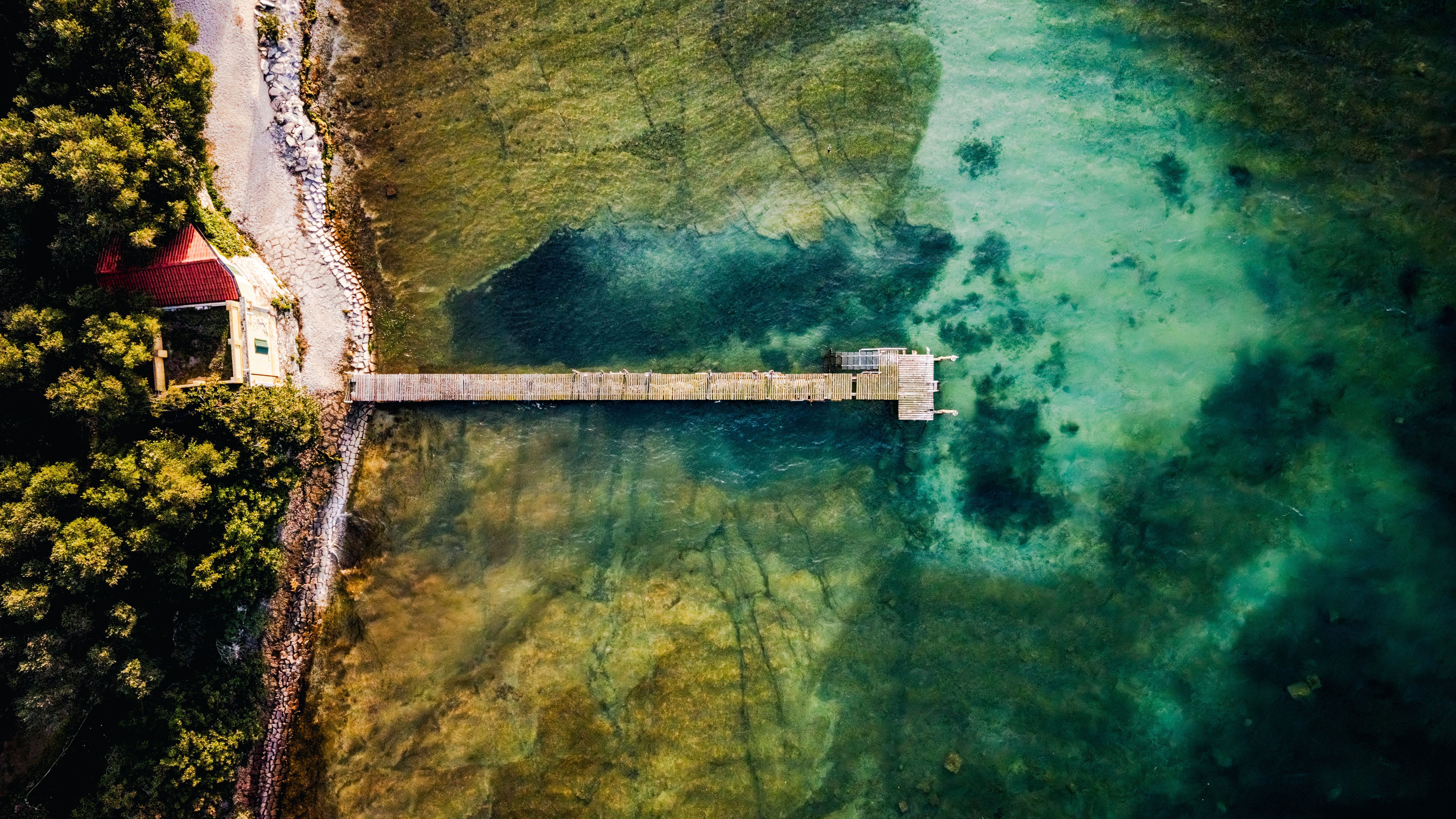 A serene aerial view of a pier extending into Lake Garda, Sirmione, Italy.