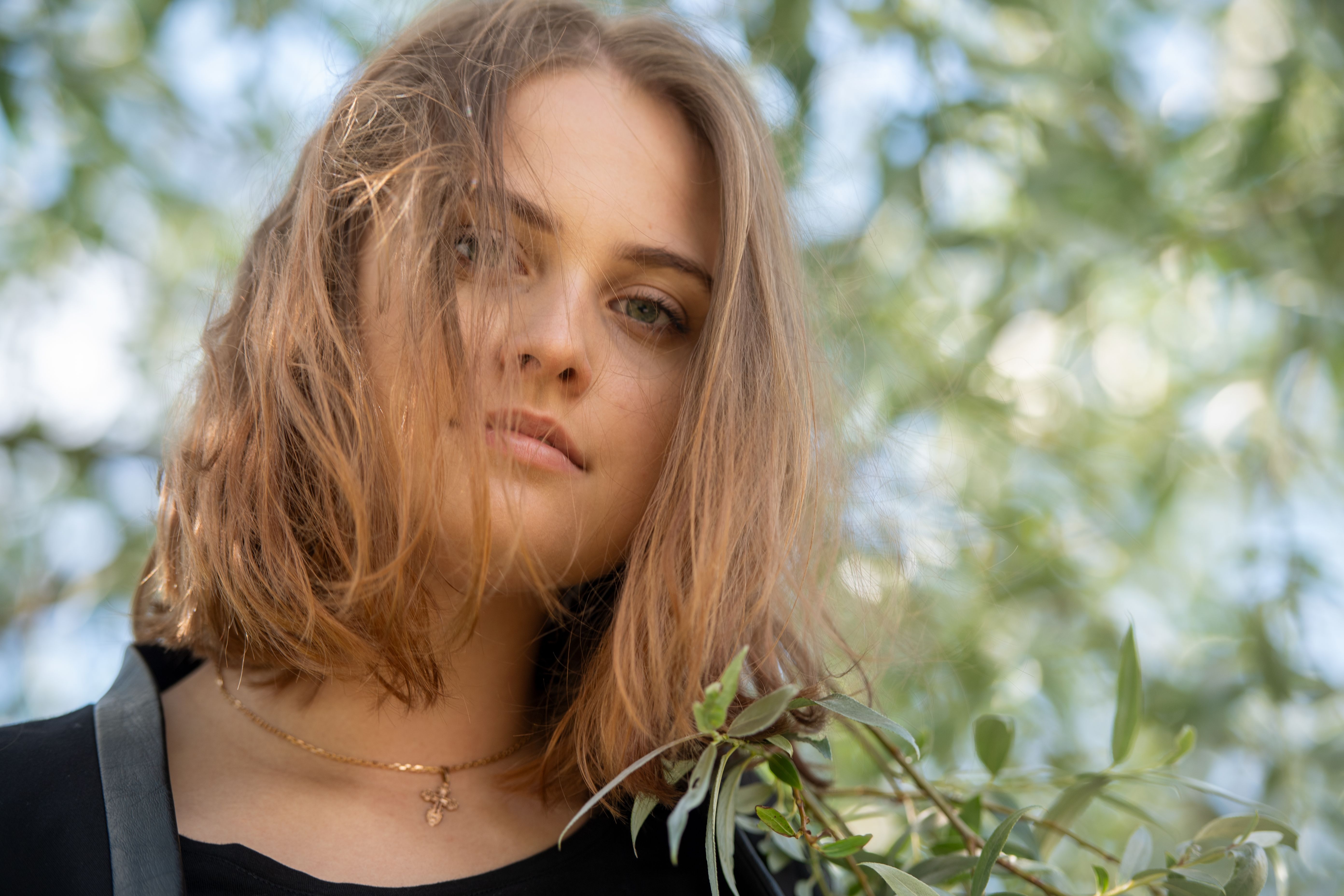 A serene portrait of a young woman enjoying a sunny day in Helsinki\'s lush Kaivopuisto Park.