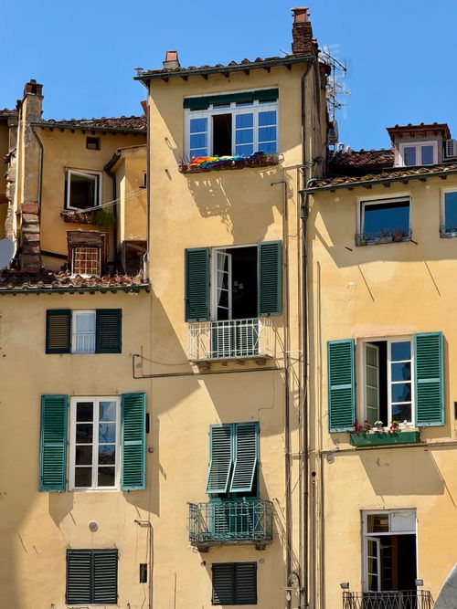 Free Sunlit rustic buildings with green shutters and balconies in Lucca, Tuscany. Stock Photo