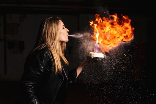 A dramatic scene of a woman blowing out candles on a fiery birthday cake with sparks flying.