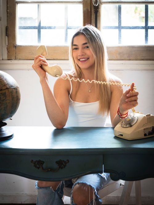 Free Happy young woman talking on a vintage phone indoors. Bright and cheerful ambiance. Stock Photo