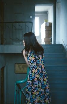 一位穿着花卉连衣裙的优雅女人，站在室内城市楼梯上，光线大气