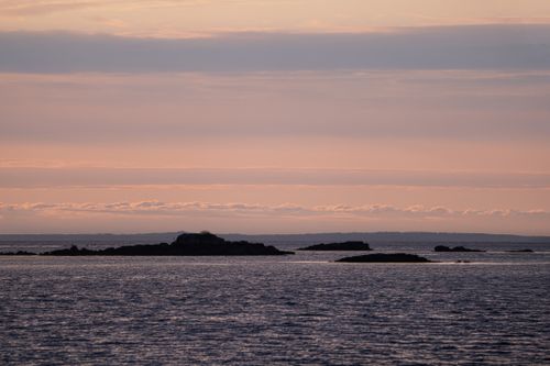 Free Peaceful sunset over the ocean with distant islands and calm waters. Stock Photo