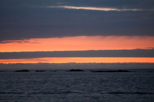 Free Serene ocean landscape with vibrant sunset hues and distant islands. Stock Photo