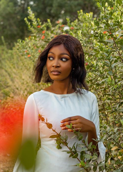 Free Elegant woman in white dress amidst vibrant greenery, showcasing natural beauty. Stock Photo