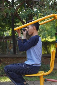 Adult male using fitness equipment in a sunny park. Health and wellness lifestyle.