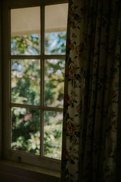 Free A floral curtain frames a bright garden view, capturing a serene indoor-outdoor ambiance. Stock Photo