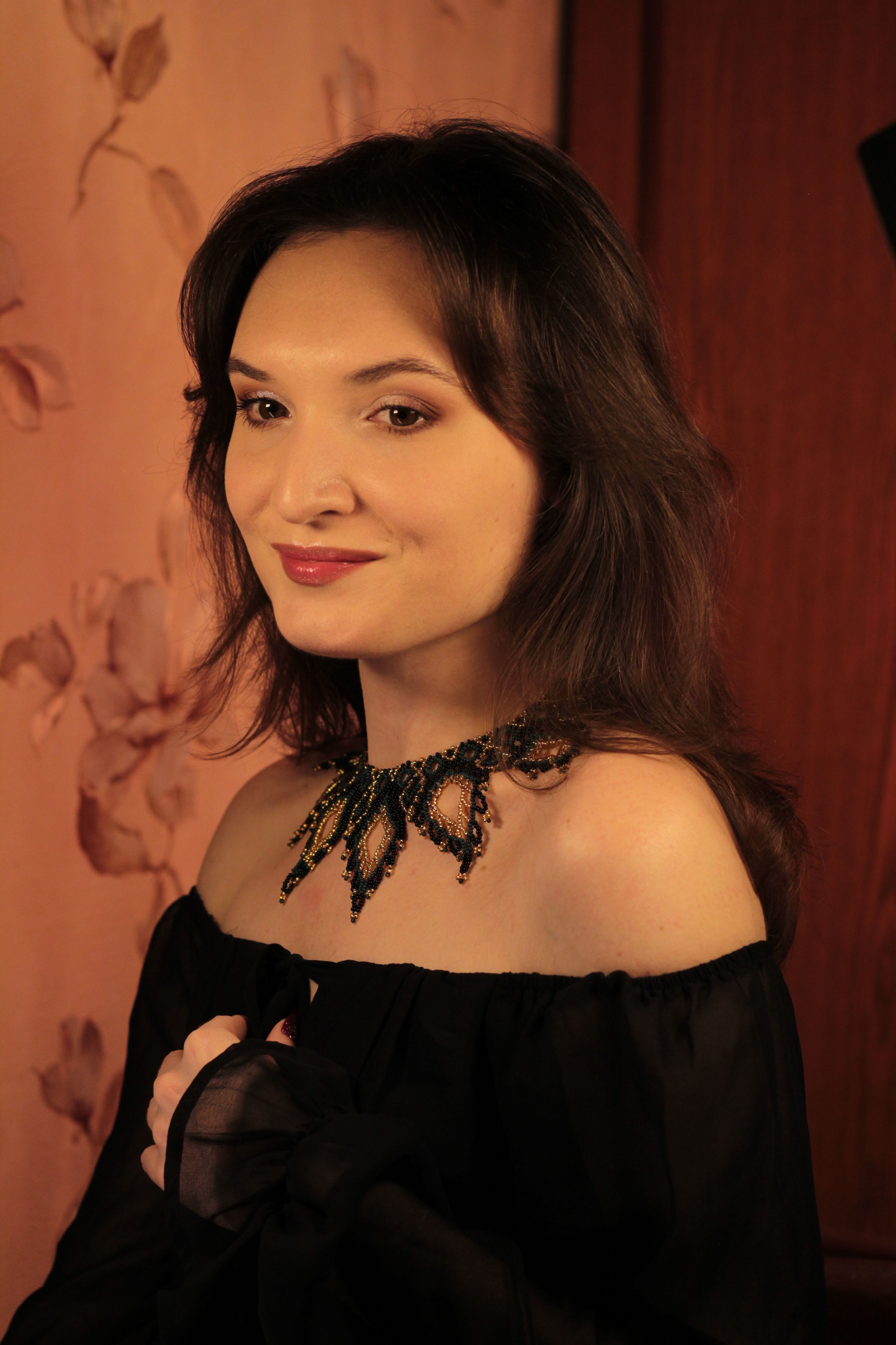 Stylish indoor portrait of a woman wearing a black dress and intricate necklace.