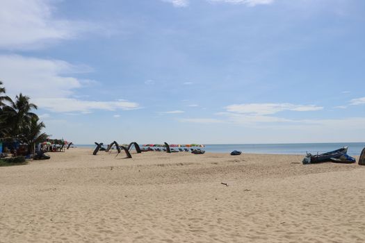 Tranquil beach with colorful umbrellas and calm ocean under a clear blue sky.