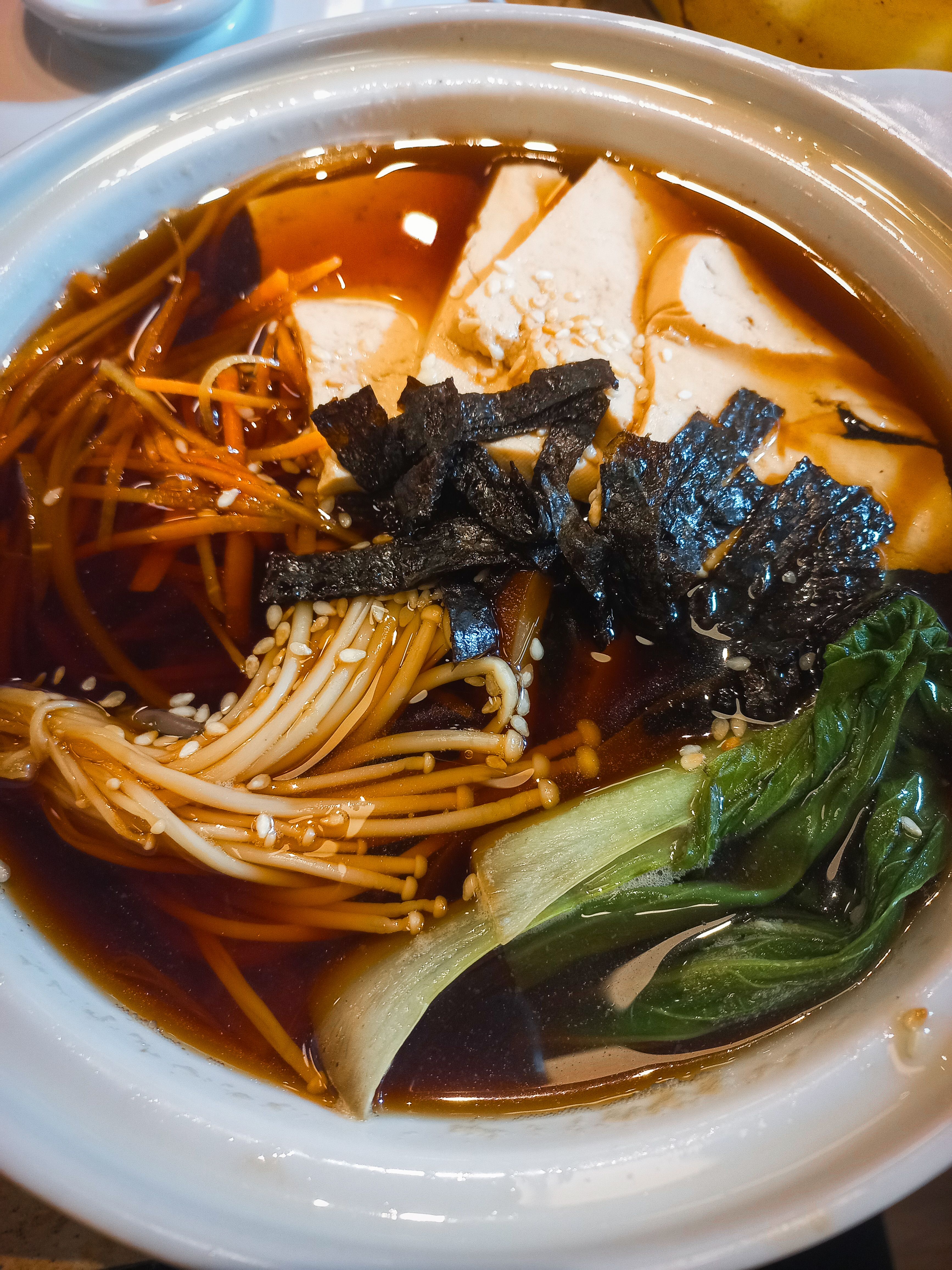 Hot and savory Asian soup featuring enoki mushrooms, tofu, seaweed, and bok choy in a rich broth.
