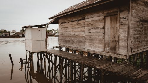 Free A rustic wooden stilt house over a serene river, reflecting traditional architecture. Stock Photo