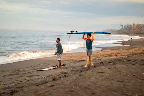 海岸のそばに立っているサーフボードを持つ男性