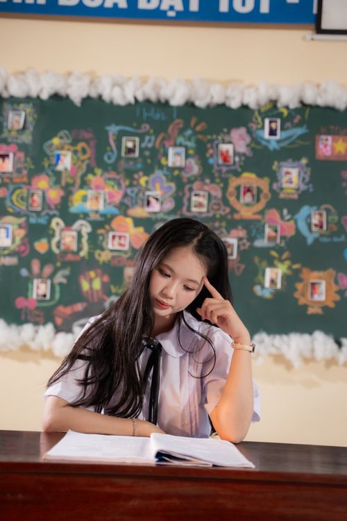 Free A student sitting at a desk in a classroom, deep in thought, with an open book. Stock Photo