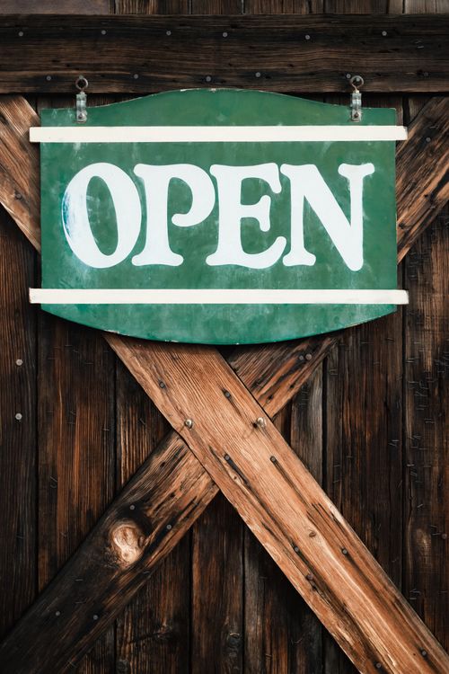 Free A rustic green 'OPEN' sign on a wooden door in Harmony, California. Stock Photo