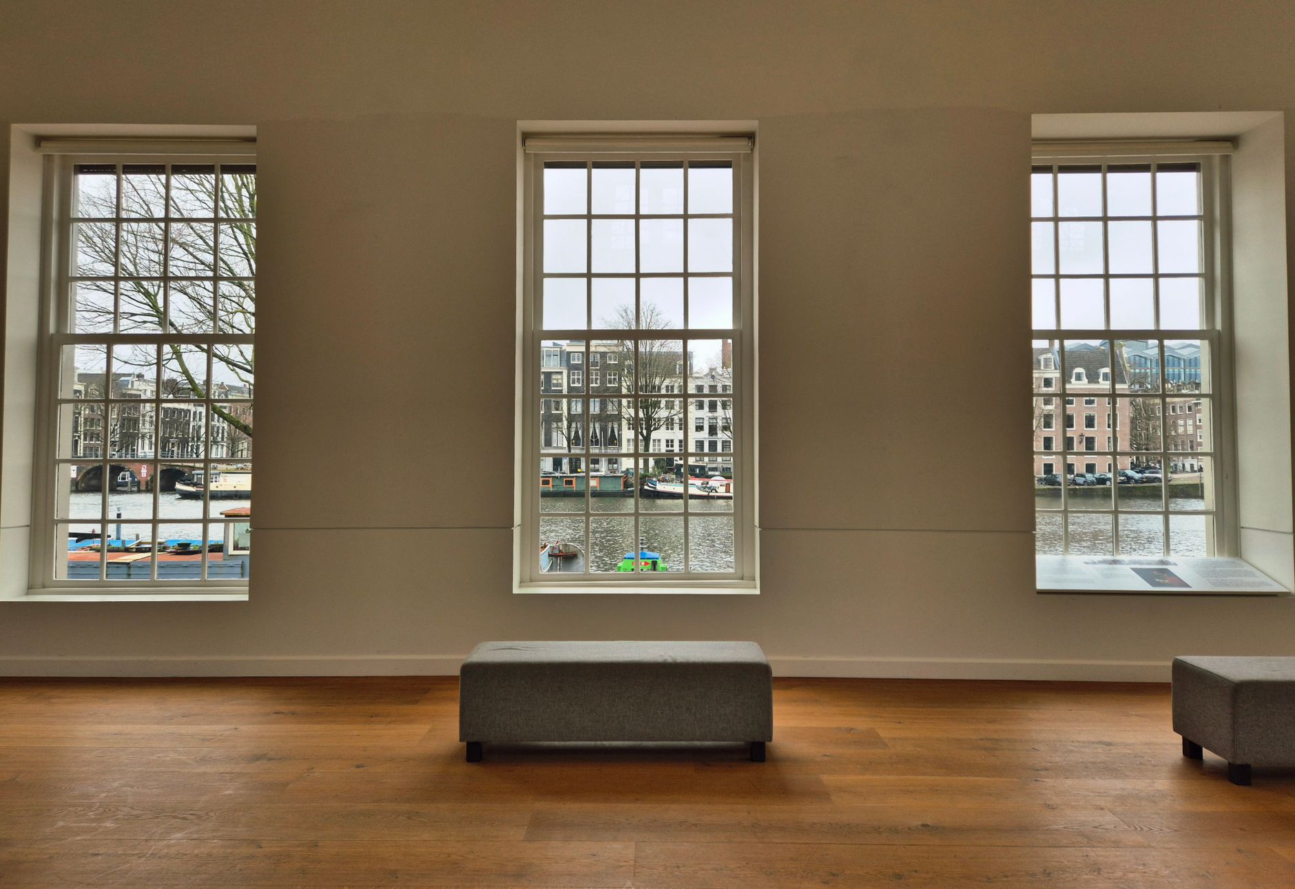 Gallery interior with large windows showcasing a scenic canal view, emphasizing architecture and tranquility.