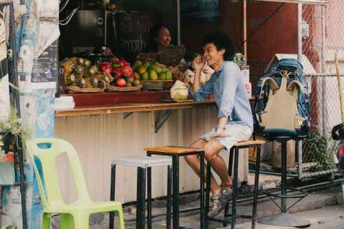 Free A lively street vendor in Chiang Mai selling fresh fruits with a smiling customer, exuding local charm. Stock Photo