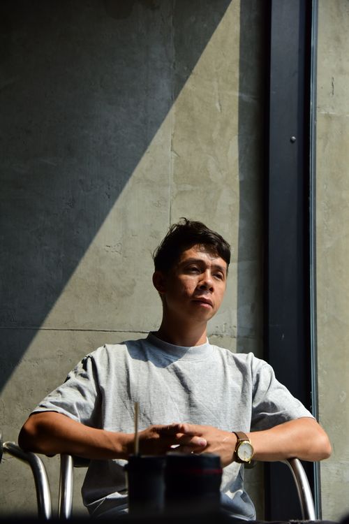 Free A man sits in a cafe, bathed in sunlight, reflecting thoughtful contemplation. Stock Photo