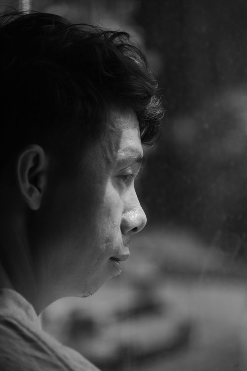 Free A thoughtful black and white portrait of a man gazing outside in reflection. Stock Photo