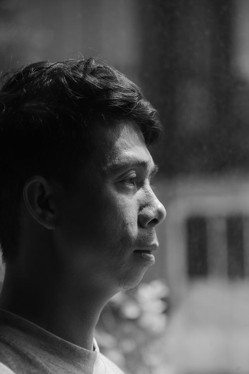 Free Thoughtful black and white portrait of an adult by a window, side profile view. Stock Photo