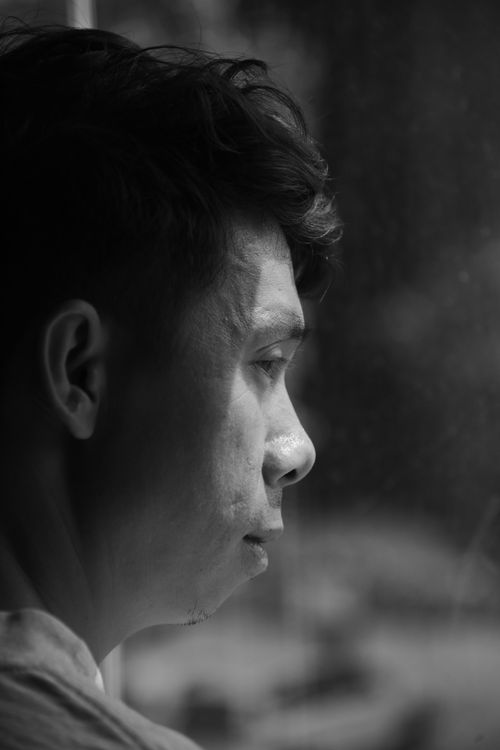 Free Black and white portrait of a man gazing out a window, deep in thought. Stock Photo