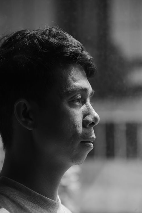 Free Side profile of a young man in deep thought, captured in black and white indoors. Stock Photo