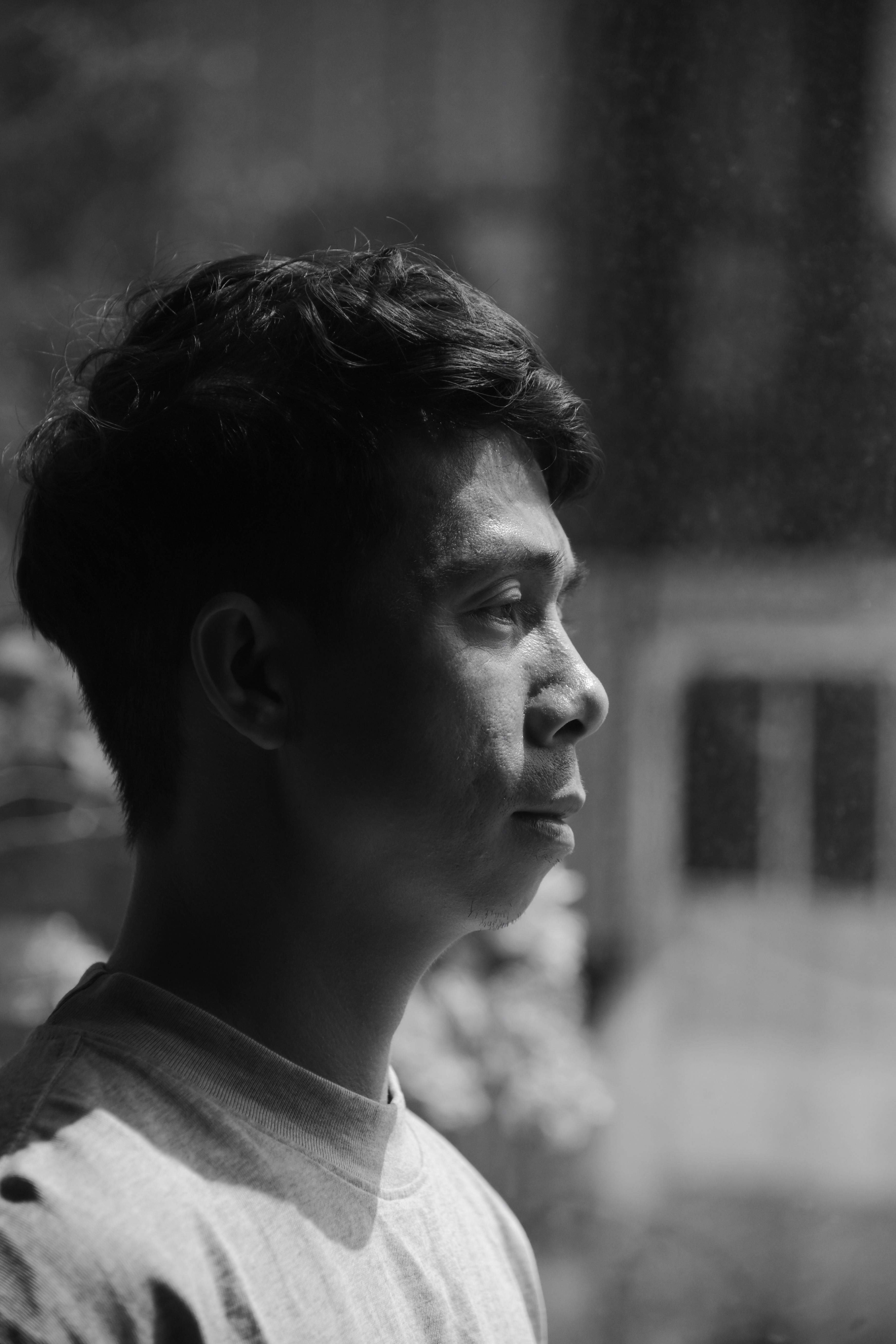 Thoughtful black and white portrait of a man looking outside a window.