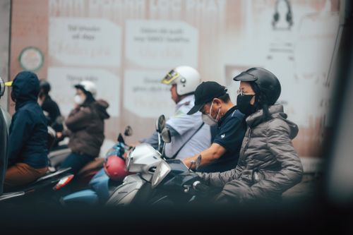 Free Busy street with people on scooters wearing masks, highlighting urban life. Stock Photo