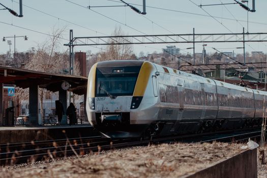 A sleek, modern train approaches Jonkoping railway station on a clear day.