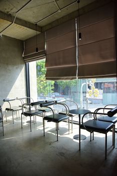 Sunlit, empty modern cafe interior with minimalist design and large window view.
