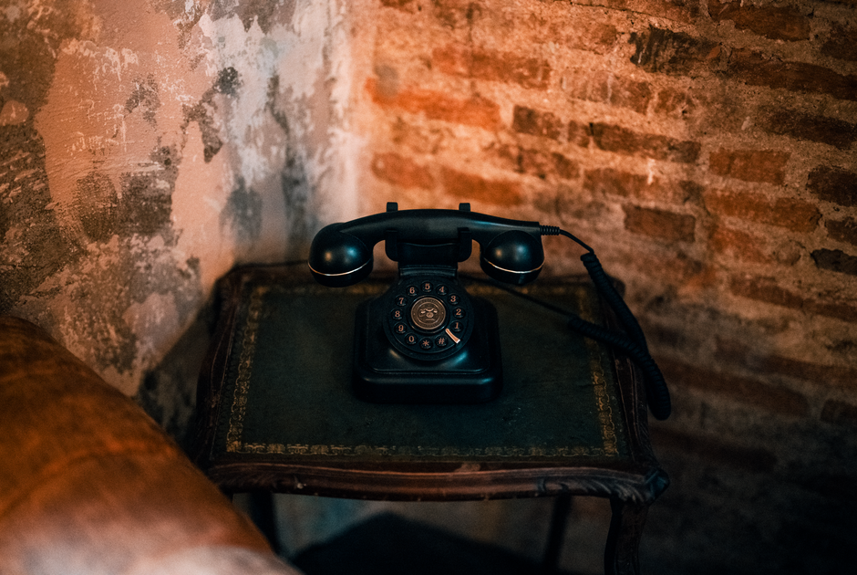 Grunge decor style interior — A classic black rotary telephone sits on an antique table by a brick wall, evoking nostalgia.