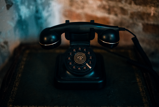 Classic black rotary telephone on a vintage table, evoking nostalgia.