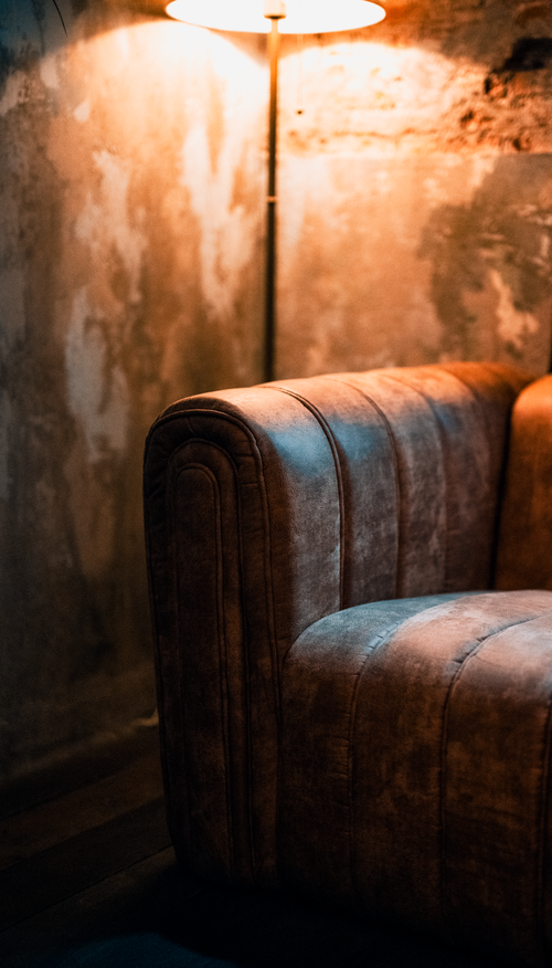 Free A warm, cozy interior scene featuring a vintage brown leather couch under ambient lighting in Bangkok. Stock Photo