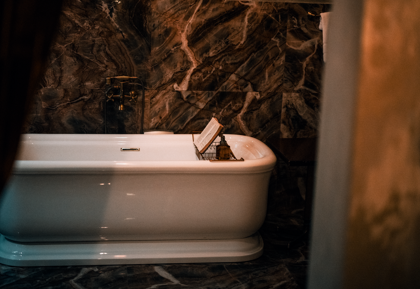 A cream marble bathroom with a classic freestanding bathtub.
