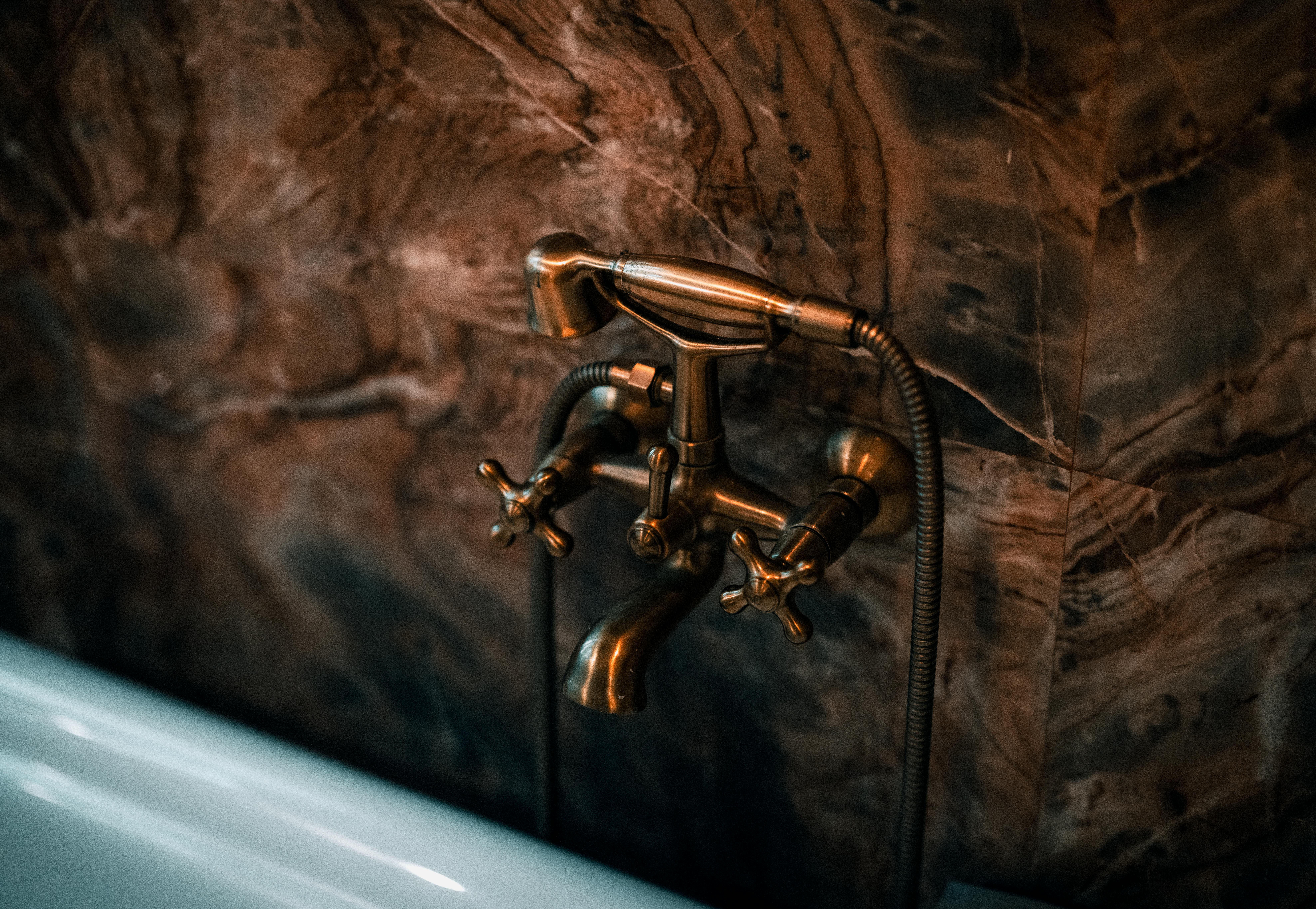 Detal instalacji pod umywalką z trójnikiem, zaworami zwrotnymi i wężem do bidetty