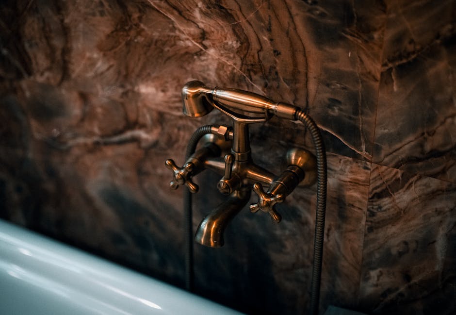 Detal instalacji pod umywalką z trójnikiem, zaworami zwrotnymi i wężem do bidetty