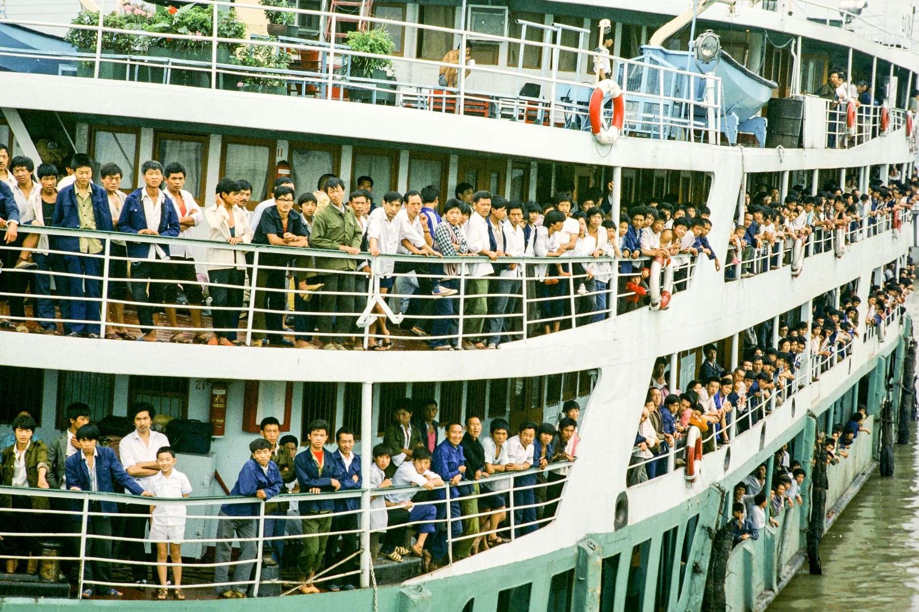 A bustling crowd of people on a multi-deck passenger ferry with vibrant activity.