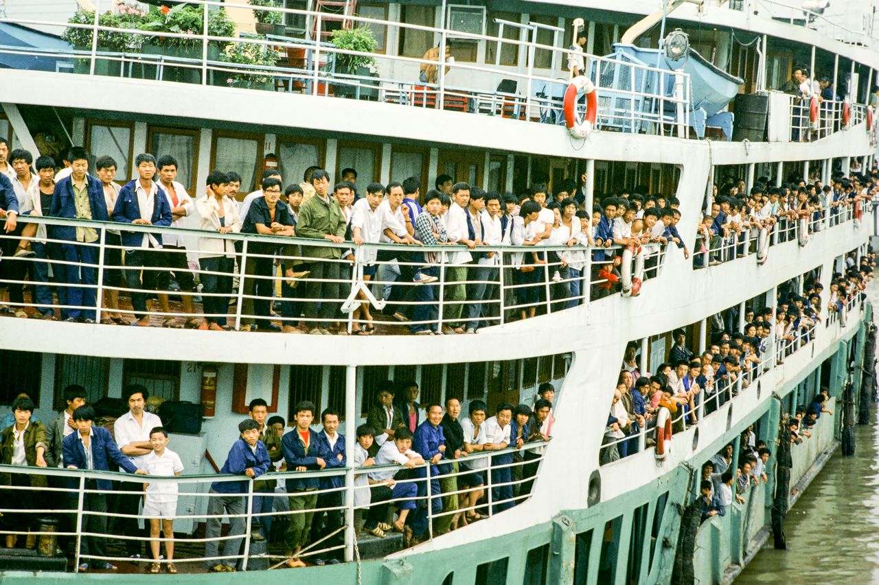 a bustling crowd of people on a multi deck passenger ferry with vibran