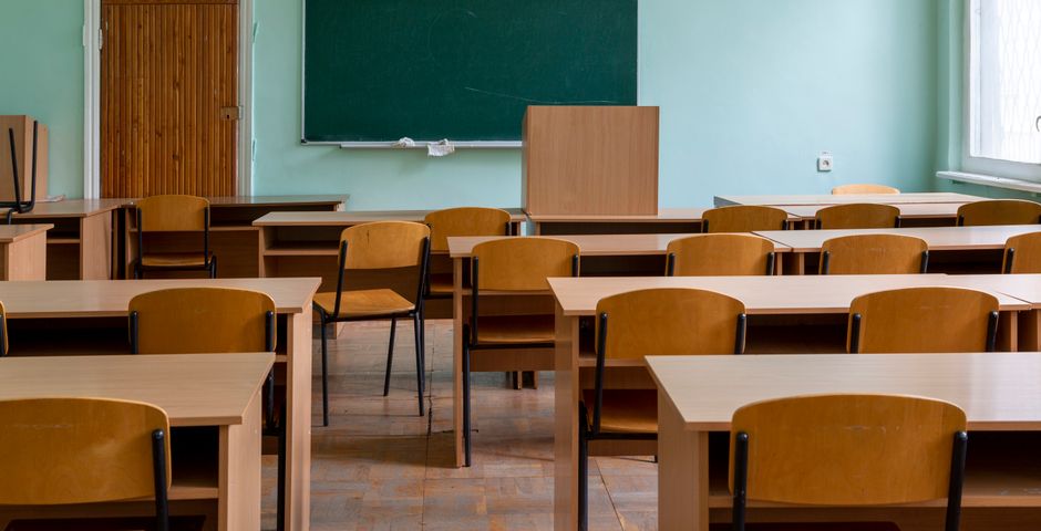 An empty classroom with wooden desks — treatment is scheduled when children aren't present