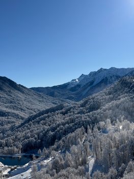Breathtaking winter landscape of snow-covered mountains in Krasnodar, Russia, under a clear blue sky.